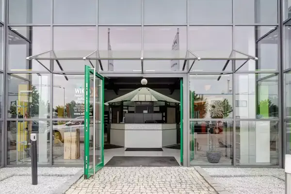 Moderner Eingangsbereich eines Geschäftsgebäudes mit Glasfassade und automatischer Tür.