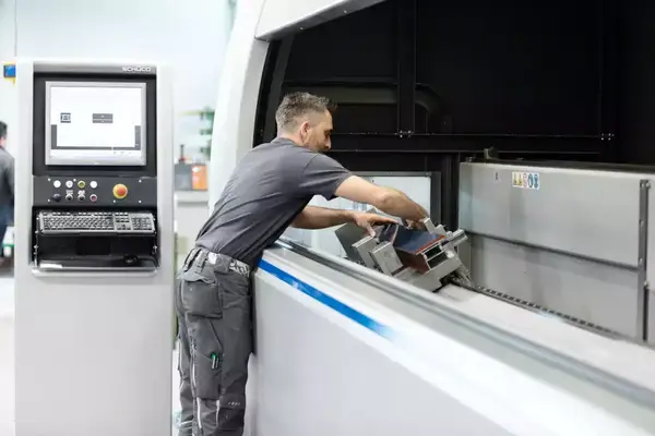 Ein Mitarbeiter bedient eine moderne CNC-Maschine zur Metallverarbeitung in der Industrie.