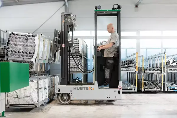 Ein Mitarbeiter bedient einen HUBTEX-Seitenstapler zur Lagerung von Aluminiumprofilen.